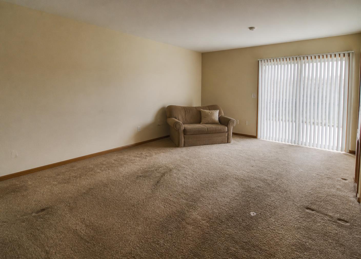 Living room before interior design in Las Vegas with dated carpet and bare walls